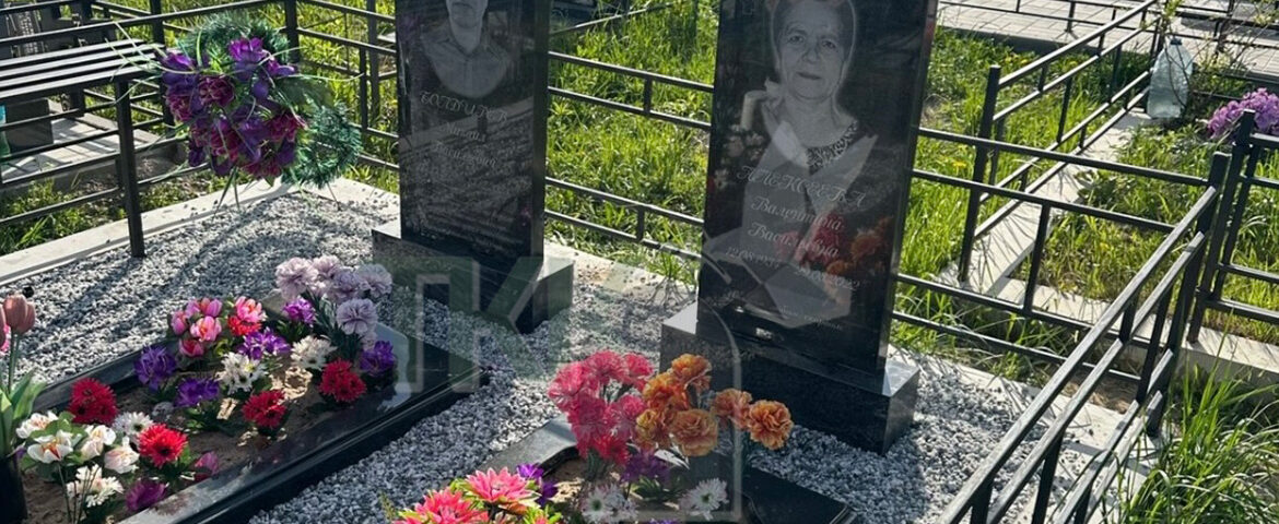 Два строгих черных памятника с большими цветниками