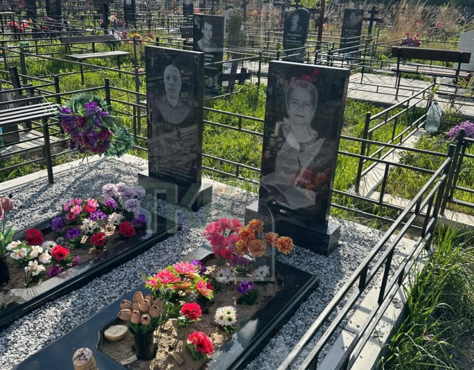 Два строгих черных памятника с большими цветниками